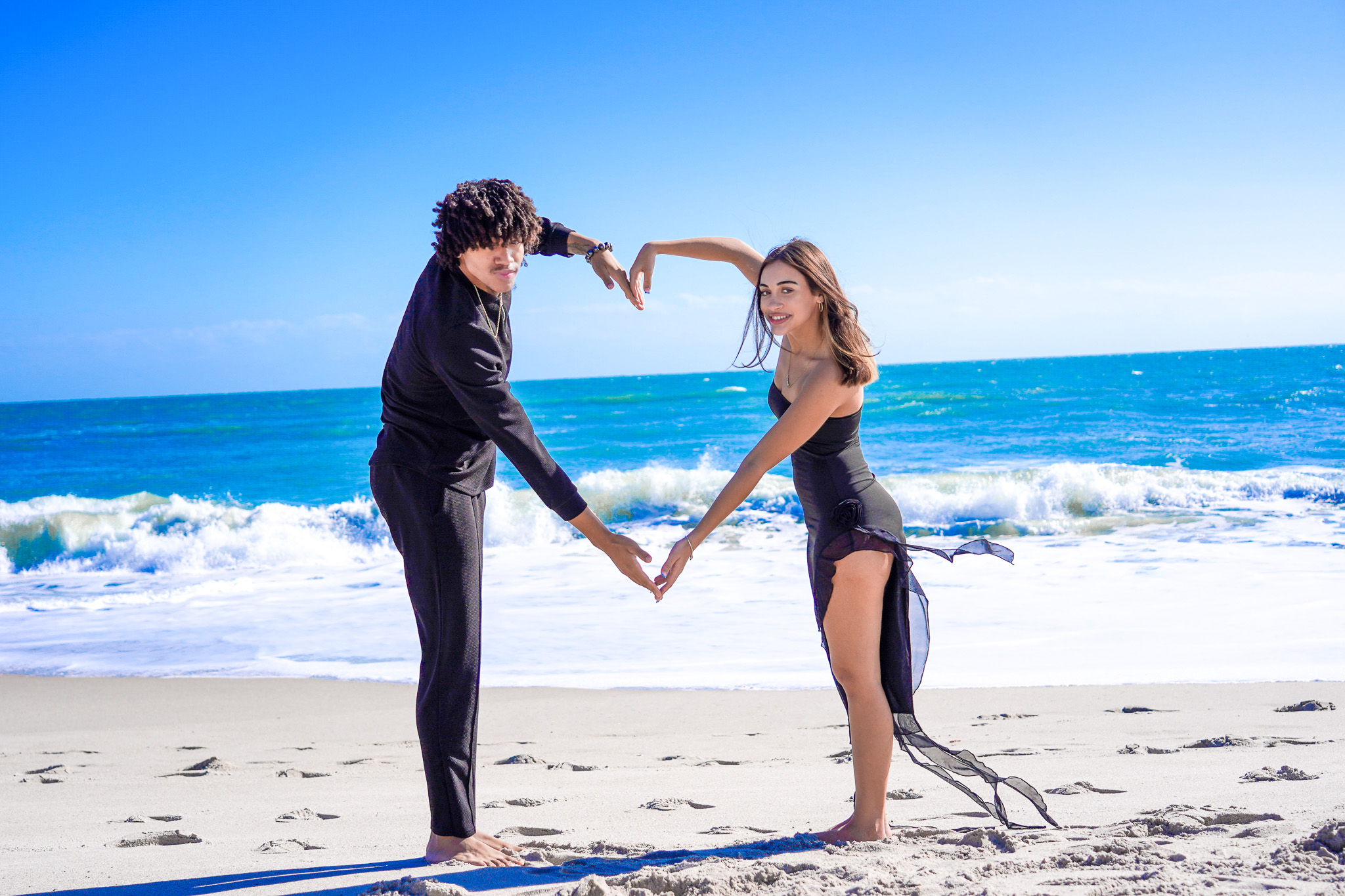 Couple forming a heart shape on the beach